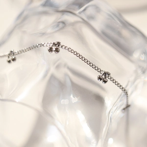 Macro shot of silver cherry pendants on a delicate chain with a wavy crystal background