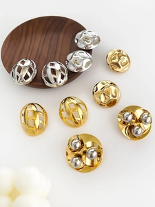 Detailed view of hollow gold and silver semi-circle earrings on a wooden tray