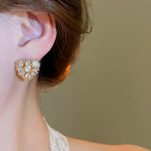 Close-up of 18k gold plated heart earrings with sparkling zircons on a model's ear