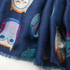 Detail of dark blue scarf featuring colorful cartoon owl prints and soft fringe edges