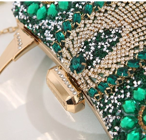 Macro shot of emerald and diamond evening clutch with gold metal frame and crystals