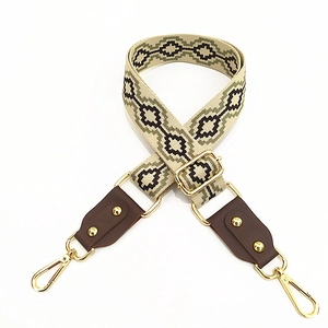Detail of ethnic jacquard strap with beige geometric patterns and gold metal swivel hooks