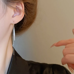 Detail shot of silver tassel earrings with zircon drop pendant worn on ear