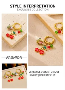 Detail of gold cherry earrings featuring red fruit charms and butterfly accents