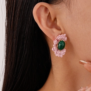 Detailed view of pink petal earrings with green oval stone worn on the earlobe