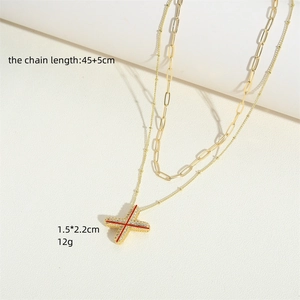 Minimalist double-layer gold plated necklace with zircon paved X pendant on beige surface