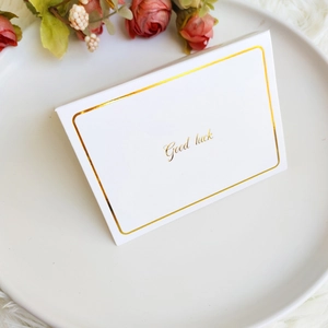 Detail einer weißen Karte mit goldener Good luck Aufschrift auf einem Keramikteller