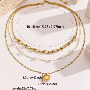 Detailansicht einer dreilagigen goldenen Halskette mit Herzanhänger und Perlen