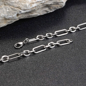 Close-up of silver stainless steel chain bracelet with lobster clasp on dark stone texture