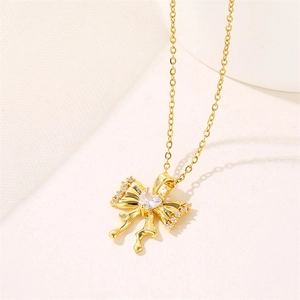 Gold stainless steel bow necklace with heart-shaped zircon pendant on textured backdrop