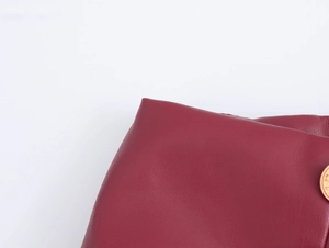Gros plan sur la texture du cuir synthétique rouge avec bouton doré en métal