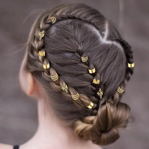 Détail de bagues de cheveux dorées et clips papillon sur une coiffure tressée complexe