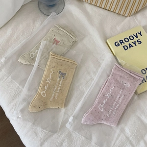 Detailed view of three pairs of embroidered bow socks in Morandi tones and packaging