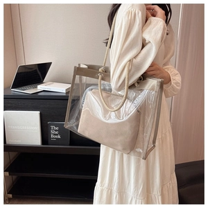 Transparent PVC tote bag with beige inner pouch and thick rope handles on a female model