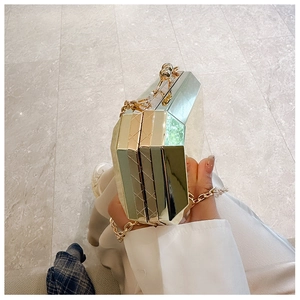 Close-up of golden geometric acrylic clutch bag with metallic chain and clasp