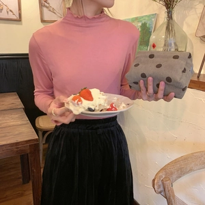 Detail view of a model holding a gray corduroy cosmetic pouch in a warm cafe setting