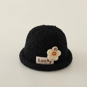 Detail eines schwarzen Fleece-Fischerhuts mit Strickblume und Lucky-Stoffetikett