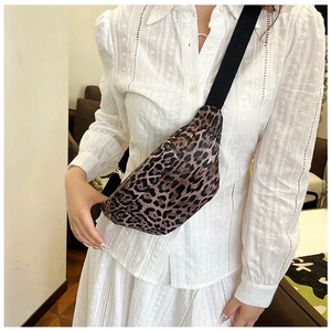 Close-up of leopard print crossbody bag with black adjustable strap worn on a model