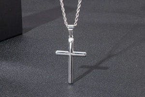 Vue macro d'un pendentif croix en argent poli sur une chaîne torsadée en métal brillant