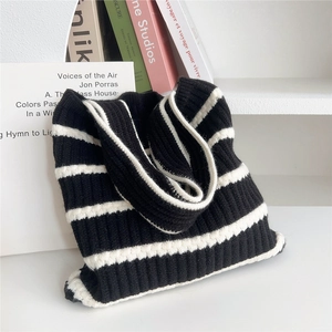 Detail der weichen Stricktextur und der schwarz-weißen Streifen einer Strick-Einkaufstasche