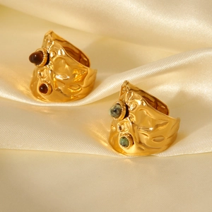 Detail of gold hammered rings with natural tiger eye and turquoise stones on cream silk
