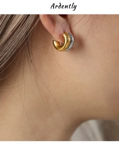 Detailed close-up of two-tone C-shape hoop earrings with gold and silver polished finish