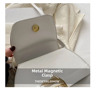 Close-up of golden magnetic metal buckle on a white leather chain bag with fine texture