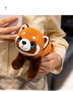 Close-up of cute red panda plush toy with TOY tag held in hands, warm and comfortable