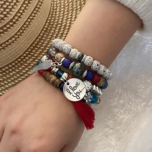 Bohemian multi-layer beaded bracelet with angel wing charms and red tassel on wrist
