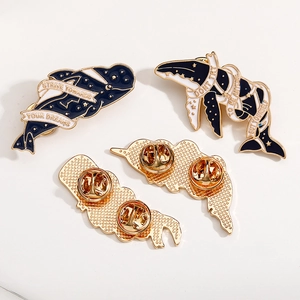 Detail der Wal-Emaille-Pins mit motivierenden Sprüchen und goldenen Schmetterlingsverschlüssen