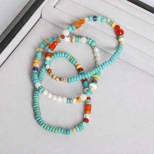 Detailed macro view of beaded bracelets with turquoise, coral, pearl, and agate on velvet tray