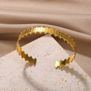Detail of gold open bangle featuring geometric grid texture and beaded edge design