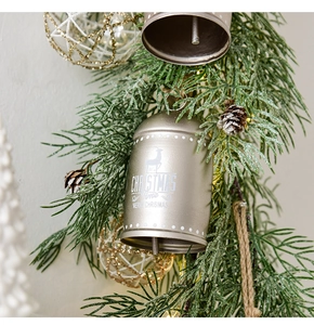 Detail einer bronzenen Weihnachtsglocke aus Metall mit Kiefernnadeln und Zapfen-Deko