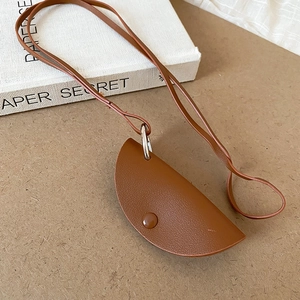 Detail of brown PU leather puppy coin purse charm with metal ring on a paper background
