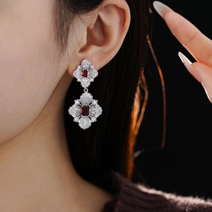 Detail of flower shaped earrings featuring sparkling zircons and red gemstones