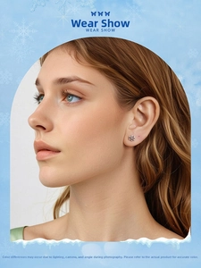 Close-up of a sparkling snowflake stud earring worn on ear showing detailed zirconia design