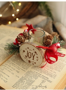 Close-up of wooden Christmas candle holder with pine cones and JOY engraving on book