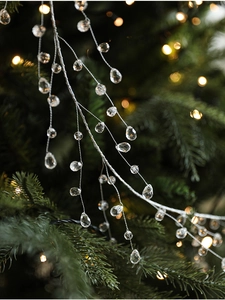 Macro detail of clear crystal bead garland hanging on a festive Christmas tree branch