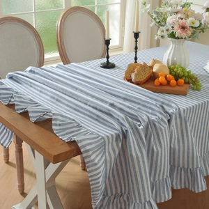 Blue and white striped tablecloth with ruffled edges on a wooden dining table