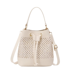 Detail of beige straw bucket bag featuring faux leather trim and adjustable strap