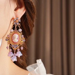 Detail of vintage gold earrings with cameo portrait, purple rhinestones and flower tassels