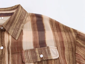Dettaglio camicia in chiffon a righe marroni con bottoni bianchi e tasca frontale