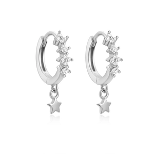 Macro shot of silver S925 earrings with sparkling zircon hoops and star-shaped pendants