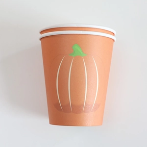 Close-up of disposable orange paper cups featuring minimalist pumpkin designs for Thanksgiving