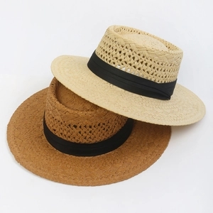 Detail of hand-woven hollow straw hat with black ribbon in beige and brown colors