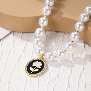 Detail of baroque pearl necklace featuring a black enamel rose pendant with diamond crystals
