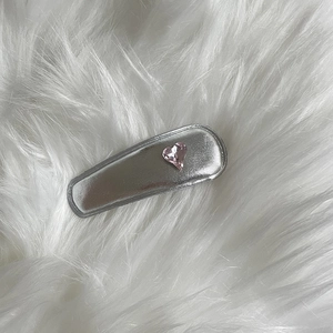 Silver rectangle hair clip with pink heart rhinestone on white plush background