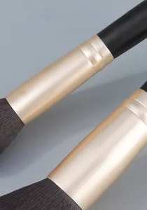Detail of thickened gold aluminum ferrule and dense black synthetic bristles for makeup brushes