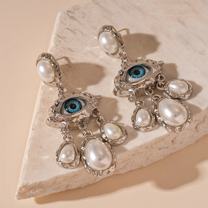 Détail de boucles d'oreilles œil en argent avec glands de perles sur marbre