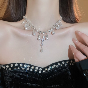 Macro detail of teardrop zircon and pearl necklace shimmering on a model's collarbone